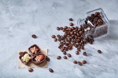 Beyaz arka planda, seçici odak devrilmiş cam sürahi kahve çekirdekleri ve çikolata şekerleme ile yan görünüm