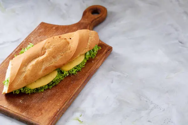 Sandwich fresco y sabroso con queso y verduras en la tabla de cortar sobre fondo de textura blanca, enfoque selectivo . —  Fotos de Stock