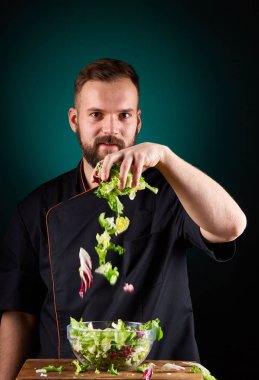 Yakışıklı bir erkek Şef portresi yemek lezzetli salata bulanık bir aquamarin arka plan yapma
