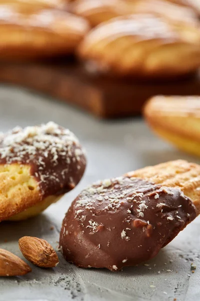 Almond cookies and raw almonds on wooden cutting board over white background, close-up, selective focus.