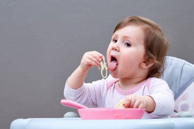 Çok güzel bebek kız gri arka plan üzerine haşlanmış sebze yemek yerken eğleniyor