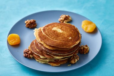Bal ve mavi arka plan, seçici odak üzerinde ceviz ile ev yapımı krep yığını
