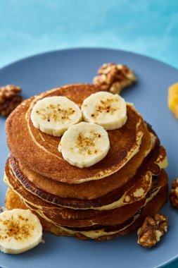 Muz ve mavi arka plan, seçici odak üzerinde ceviz ile ev yapımı krep yığını