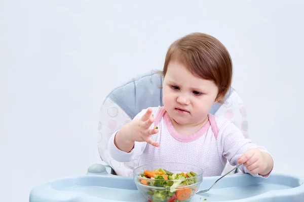 Очаровательная девочка-младенец веселится во время еды тушеные овощи на белом фоне — стоковое фото