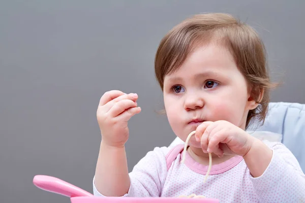 Menina da criança adorável está se divertindo enquanto come legumes cozidos no fundo cinza — Fotografia de Stock