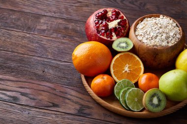 Bir kase yulaf ezmesi gevreği rustik arka plan üzerinde düz ahşap tepsi üzerinde meyve ile servis yatıyordu, seçici odak