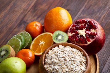 Bir kase yulaf ezmesi gevreği rustik arka plan üzerinde düz ahşap tepsi üzerinde meyve ile servis yatıyordu, seçici odak