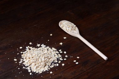 Devrilmiş cam kavanoz ve kaşık vintage ahşap arka plan, yakın çekim, seçici odak çiğ yulaf ezmesi ile.