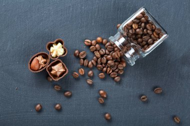 Ahşap zemin, seçici odak üzerine devrilmiş cam sürahi kahve çekirdekleri ve çikolata şekerleme ile yan görünüm