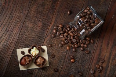 Ahşap zemin, seçici odak üzerine devrilmiş cam sürahi kahve çekirdekleri ve çikolata şekerleme ile yan görünüm
