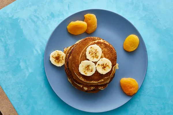 Högen av hemlagade pannkakor med valnötter på blåaktig tallrik över Blå bakgrund, selektivt fokus — Stockfoto