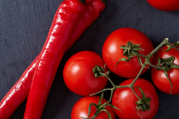 Composición de manojo de tomate y pimiento picante en la pieza de cartón negro, vista superior, primer plano . — Foto de Stock