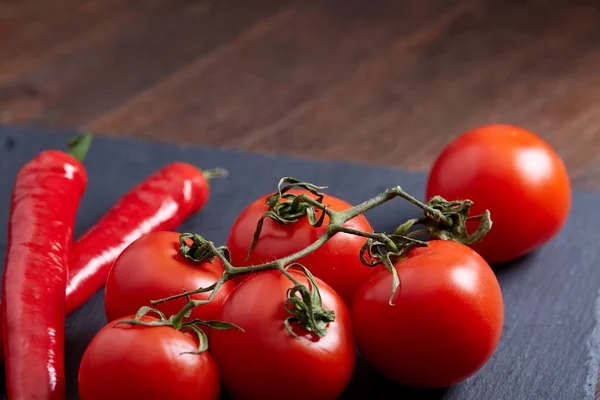 Composición de manojo de tomate y pimiento picante en la pieza de cartón negro, vista superior, primer plano . — Foto de Stock