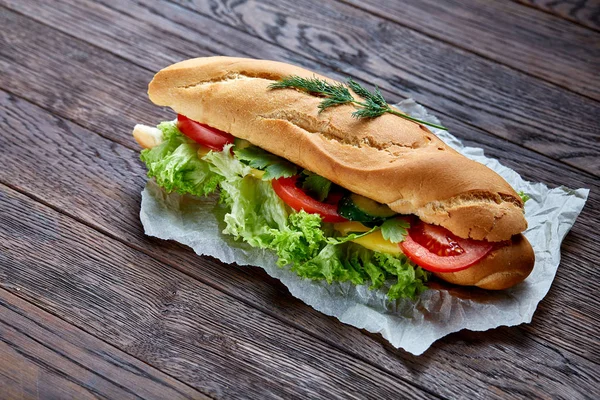 Fresh and tasty sandwich with cheese and vegetables on paper napkin over wooden background, selective focus, top view — Stock Photo, Image