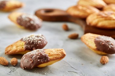 Bademli kurabiyeleri ve ahşap kesme tahtası beyaz arka plan, yakın çekim, seçici odak üzerinde çiğ badem.