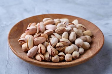 Beyaz arka plan, üstten görünüm, yakın çekim, seçici odak ahşap bir tabakta tuzlu fıstık.