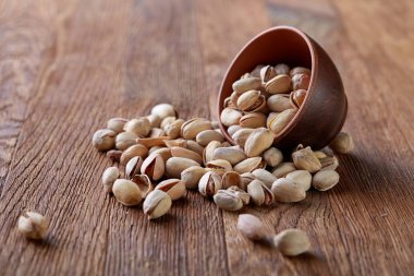 Pistachious ahşap arka plan, üstten görünüm, seçici odak ile devrilmiş seramik kase.