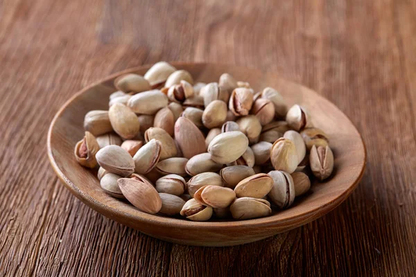 Ahşap arka plan, üstten görünüm, yakın çekim, seçici odak ahşap bir tabakta tuzlu fıstık.