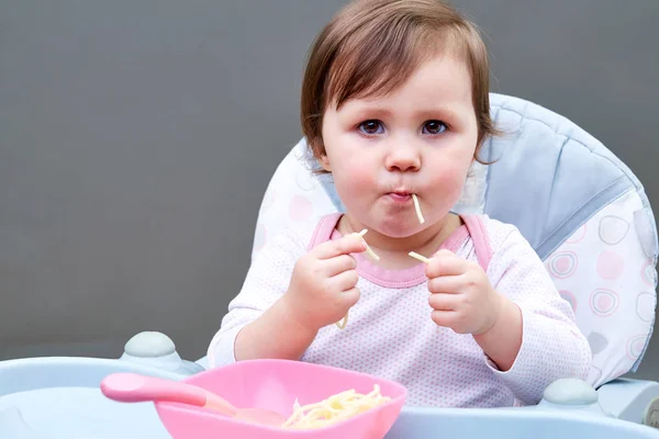 Menina da criança adorável está se divertindo enquanto come legumes cozidos no fundo cinza — Fotografia de Stock
