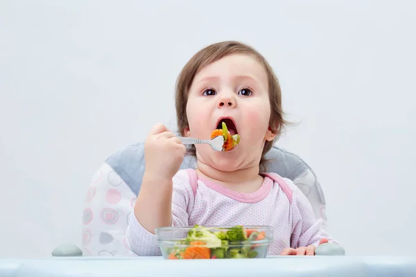 Adorabile bambina si sta divertendo mentre mangia verdure stufate su sfondo bianco — Foto Stock