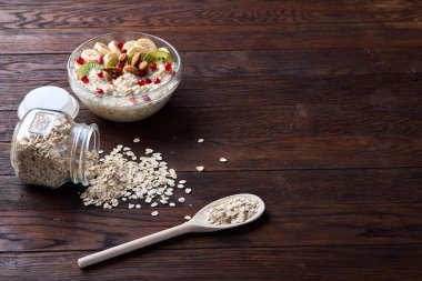 Devrilmiş cam kavanoz ve kaşık vintage ahşap arka plan, yakın çekim, seçici odak çiğ yulaf ezmesi ile.