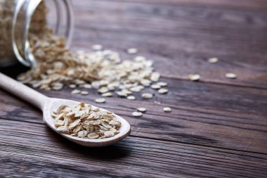 Devrilmiş cam kavanoz ve kaşık vintage ahşap arka plan, yakın çekim, seçici odak çiğ yulaf ezmesi ile.