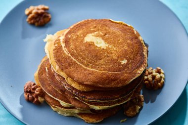 Bal ve mavi arka plan, seçici odak üzerinde ceviz ile ev yapımı krep yığını