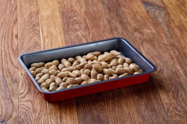 Tepsi ahşap arka plan, seçici odak, sığ derinlik-in tarla üzerinde pişirme üzerinde soyulmamış çiğ fıstık.