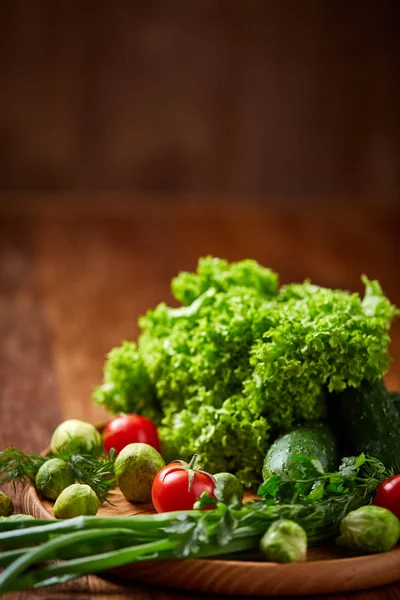 Nature morte végétarienne de légumes frais sur assiette en bois sur fond rustique, gros plan, plat . — Photo