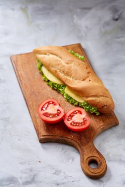 Taze ve lezzetli sandviç peyniri ve sebze kesme tahtası üzerinde beyaz dokulu arka plan, seçici odak üzerinde.