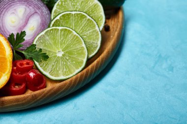 Natürmort mavi arka plan, seçici odak, yakın çekim ahşap plaka üzerinde taze organik sebze