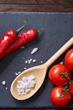 Taze üzüm domates, biber ve tuz ahşap zemin, seçici odak üzerine tahta kaşık ile vejetaryen natürmort