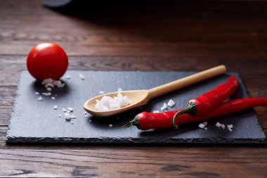 Taze üzüm domates, biber ve tuz ahşap zemin, seçici odak üzerine tahta kaşık ile vejetaryen natürmort