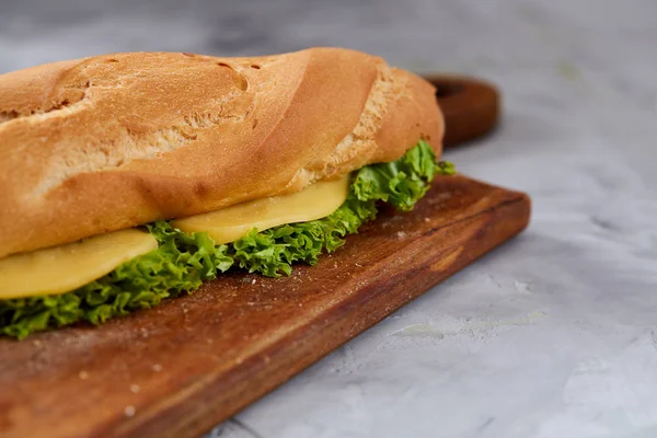 Sandwich fresco y sabroso con queso y verduras en la tabla de cortar sobre fondo de textura blanca, enfoque selectivo . —  Fotos de Stock