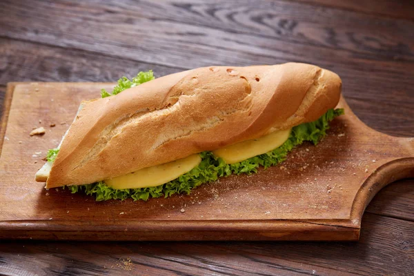 Sandwich fresco y sabroso con queso y verduras en tabla de cortar sobre fondo de madera, enfoque selectivo . —  Fotos de Stock