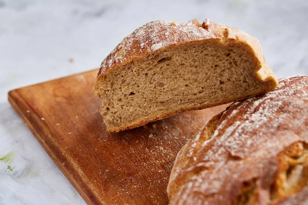 Friss Rozsos kenyér kenyér-egy fa vágódeszka a fedélzet felett fehér textúrázott háttérre, sekély mélység-ból mező — Stock Fotó