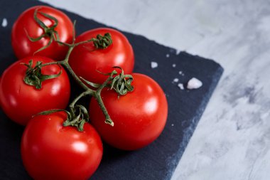 Taze domates ve bir kaşık tuz beyaz arka plan, yakın çekim, seçici odak Siyah Taşlı gemide.