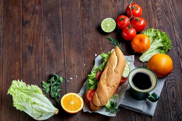 Fresh sandwich with lettuce, tomatoes, cheese on wooden plate, cup of coffee on wooden background, selective focus — Stock Photo, Image