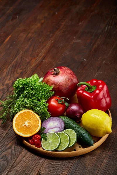 Still life of fresh organic vegetables on wooden plate over wooden background, selective focus, close-up