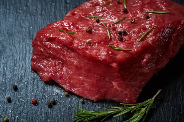 Çiğ et dana biftek siyah üzerine kurulu baharat ve biberiye ile ahşap arka plan üzerinde kopya alanı kayrak