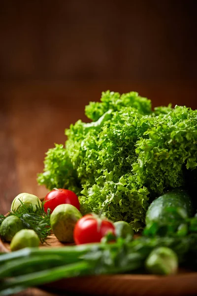 Nature morte végétarienne de légumes frais sur assiette en bois sur fond rustique, gros plan, plat . — Photo