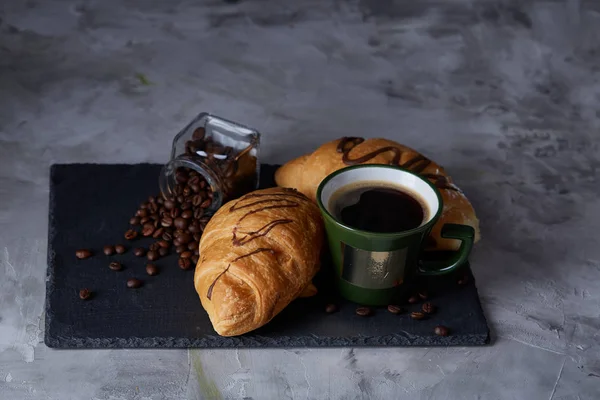 Xícara de café, jarra com grãos de café, croissants na placa de pedra sobre fundo branco, foco seletivo, close-up — Fotografia de Stock