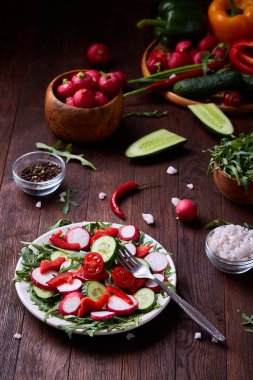 Yaratıcı taze sebze salatası ruccola, salatalık, domates ve beyaz plaka, seçici odak üzerinde raddish