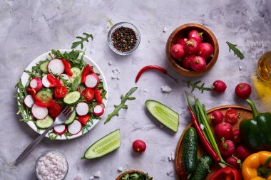 Yaratıcı taze sebze salatası ruccola, salatalık, domates ve beyaz plaka, seçici odak üzerinde raddish