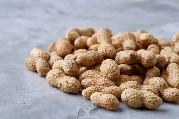 Pile of shelled peanuts isolated on white background, top view, close-up, vertical, shallow depth of field