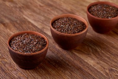Ahşap arka plan, üstten görünüm, seçici odak satırda flaxseeds arrenged ile üç seramik kaseler