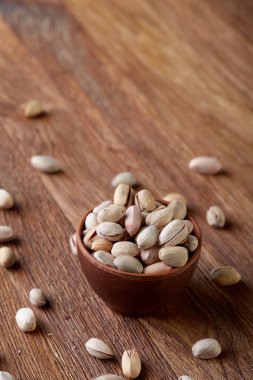 Pistachious ahşap arka plan, üstten görünüm, seçici odak ile devrilmiş seramik kase.