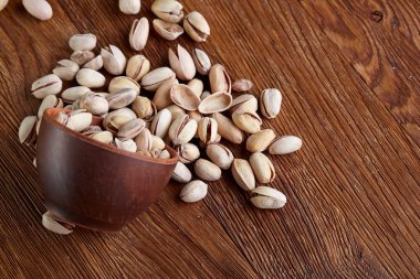 Pistachious ahşap arka plan, üstten görünüm, seçici odak ile devrilmiş seramik kase.