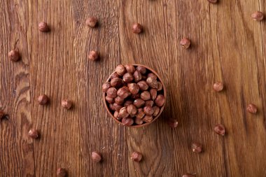 Kopya alanı, üstten görünüm, seçici odak ahşap zemin üzerine devrilmiş seramik kase fındık.