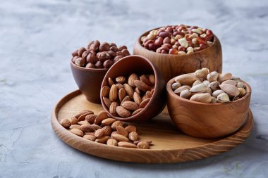 Beyaz arka plan, yakın çekim, en iyi görünüm, seçici odak ahşap tepsi üzerinde kahverengi kase karışık Kuruyemiş.